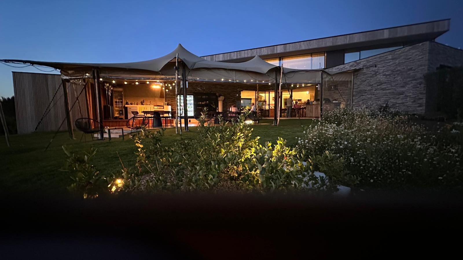 Avondzicht op het overdekte terras en het verlichte salon